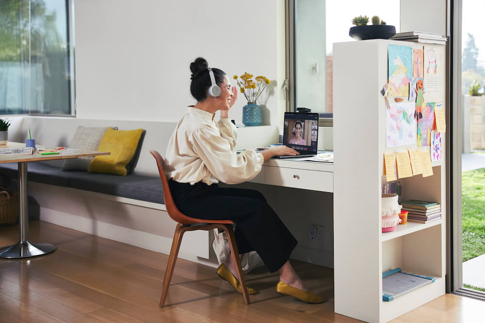 Eine Frau nimmt über die Webex Desk Camera und das Cisco 730 Headset aus dem Homeoffice an einem Meeting teil