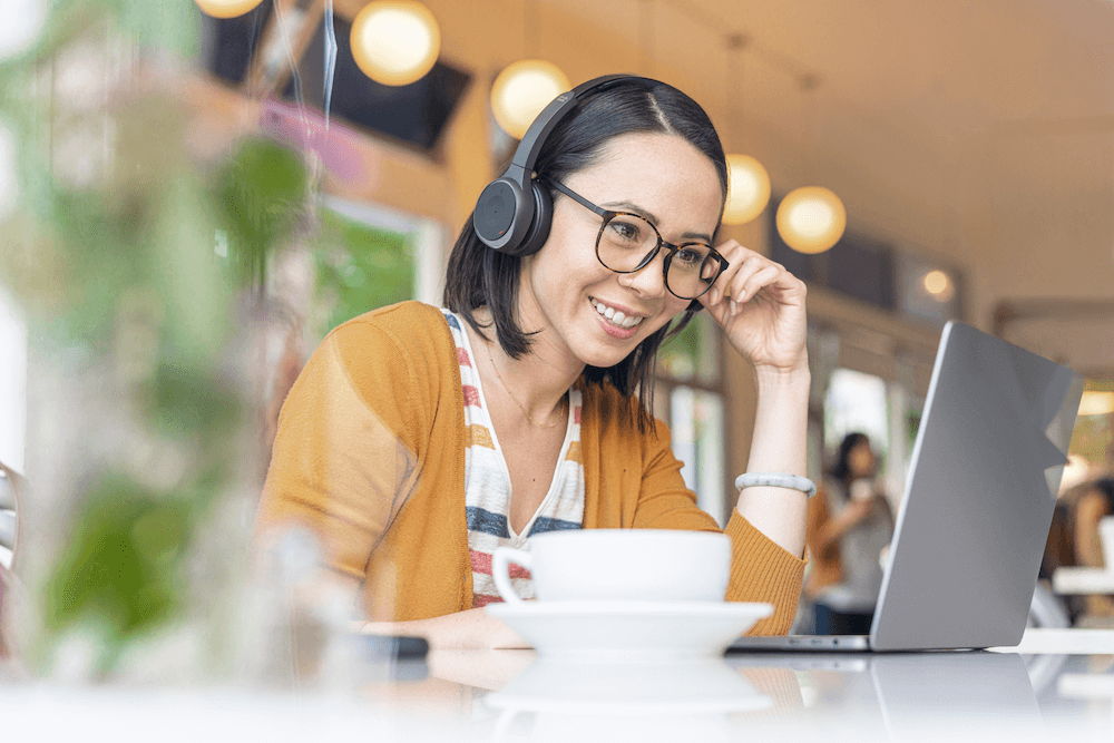 Eine Frau nutzt das Cisco 730 Headset f&uuml;r eine gute Audioqualit&auml;t bei Onlinemeetings aus dem Caf&eacute;