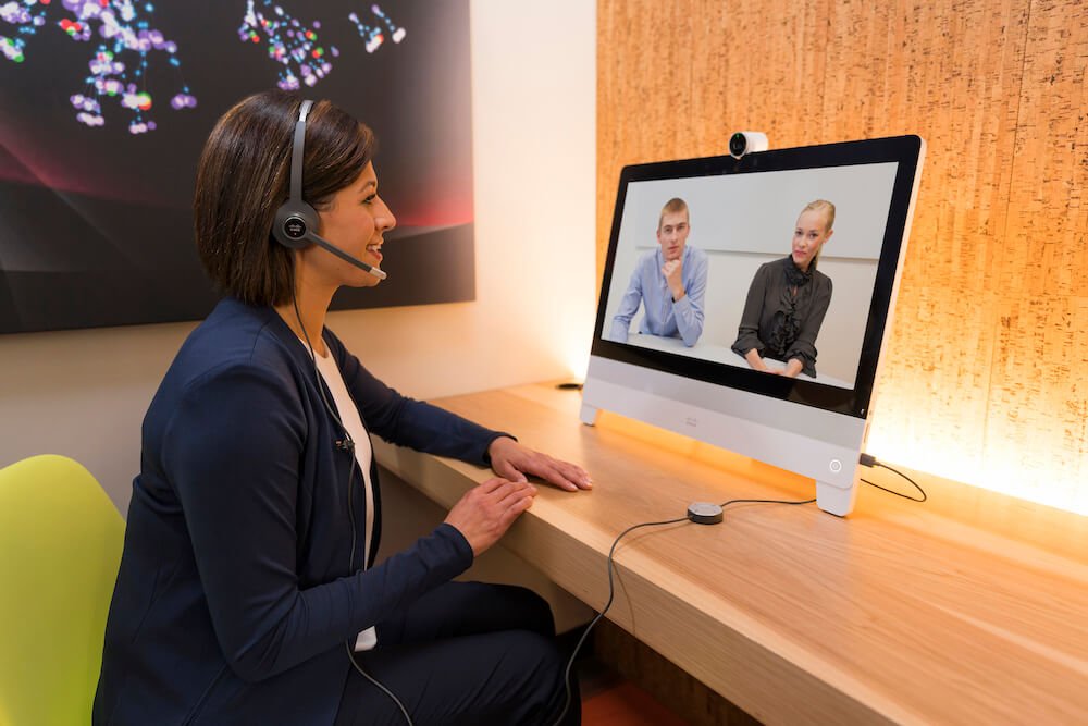 Eine Frau nutzt das kabelgebundene Headset und die DX80 f&uuml;r ihr Onlinemeeting