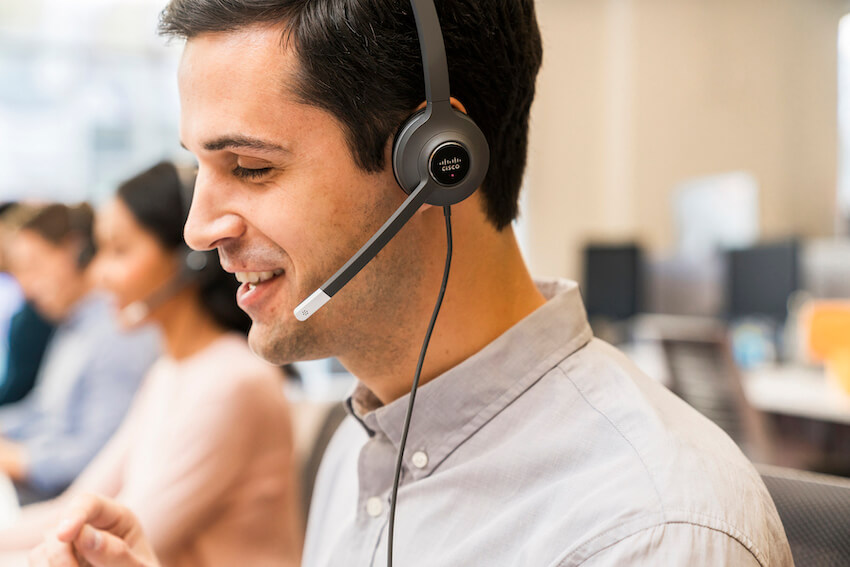Ein Mann telefoniert &uuml;ber sein kabelgebundenes Headset im B&uuml;ro