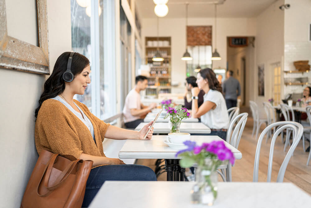 Eine Frau trägt in einem Café das Cisco 730 Headset und liest