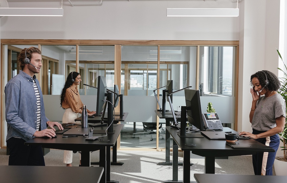 3 Mitarbeiter befinden sich im Büro und telefonieren über ihre Headsets