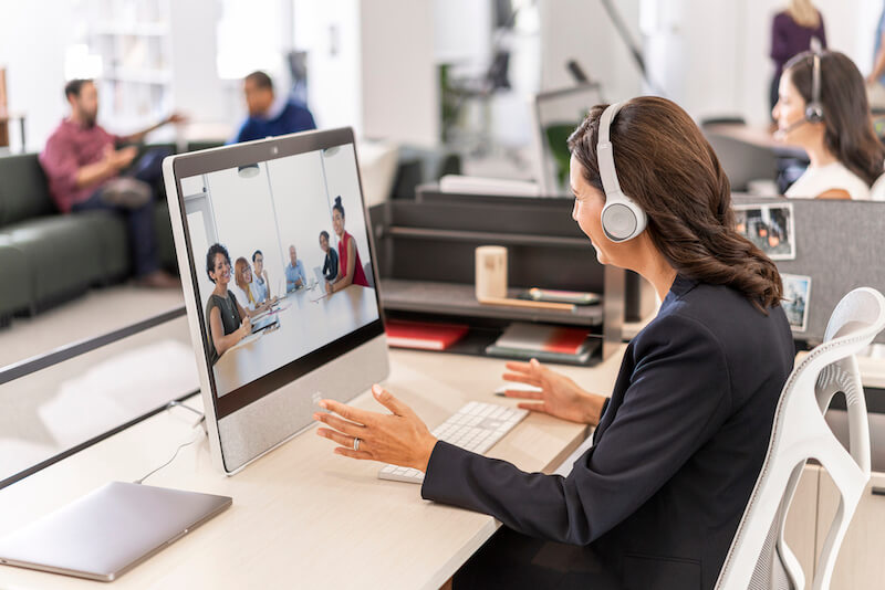 Eine Frau nutzt das Cisco 730 Headset und die Webex Desk für Videomeetings aus dem Büro