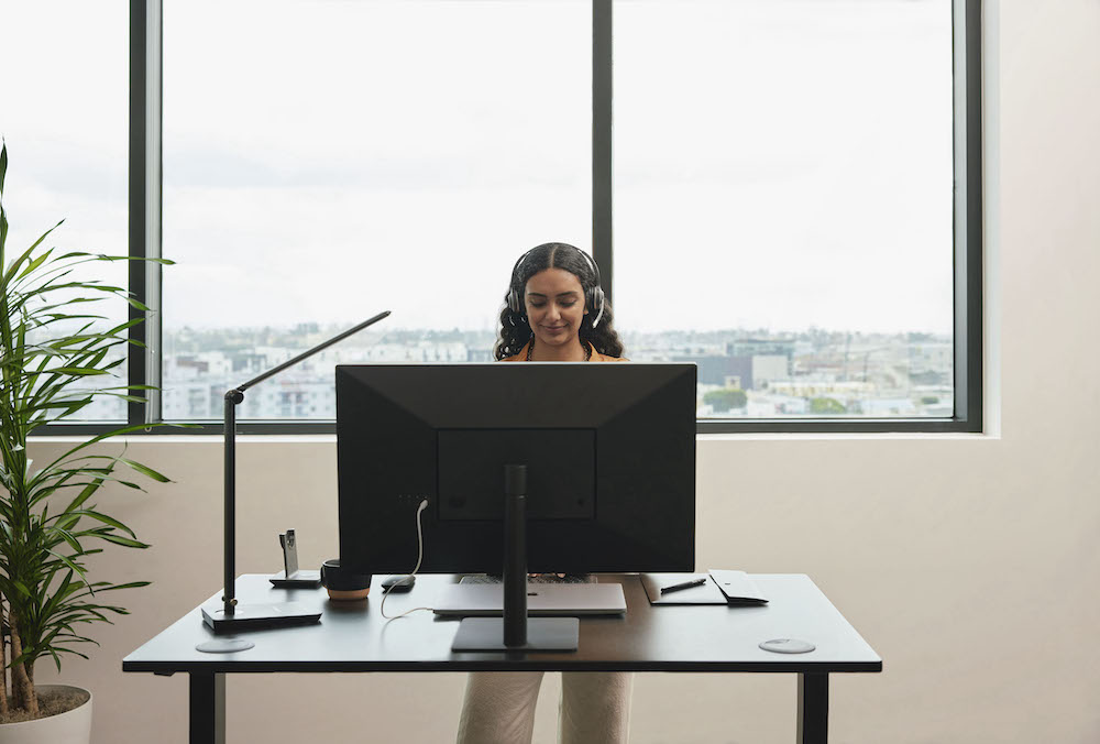 Eine Frau telefoniert &uuml;ber ihr Headset, w&auml;hrend sie den Computer bedient