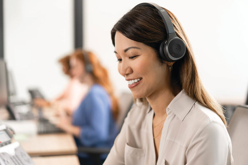 Eine lächelnde Frau telefoniert im Büro über das Cisco 730 Headset