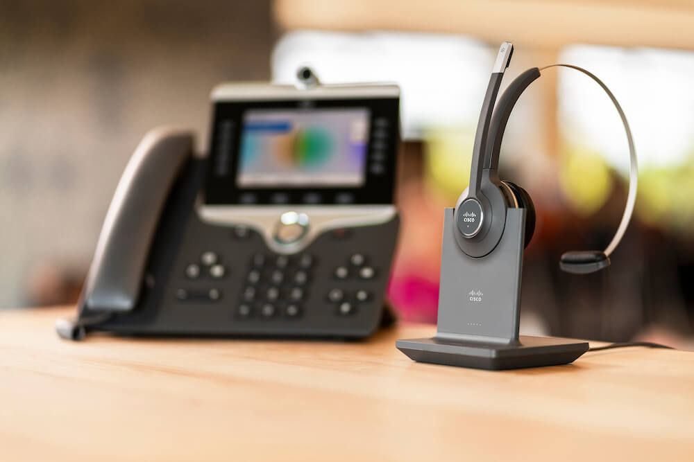Das Cisco-Telefon steht neben dem kabellosen Headset auf dem Tisch
