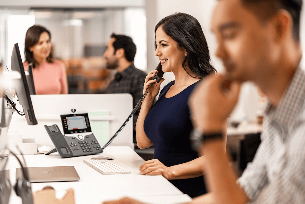 Eine Frau telefoniert im B&uuml;ro mit ihrem Cisco IP-Telefon
