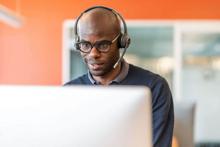 Ein Mann telefoniert &uuml;ber das Headset und gibt gleichzeitig Daten in den Computer ein