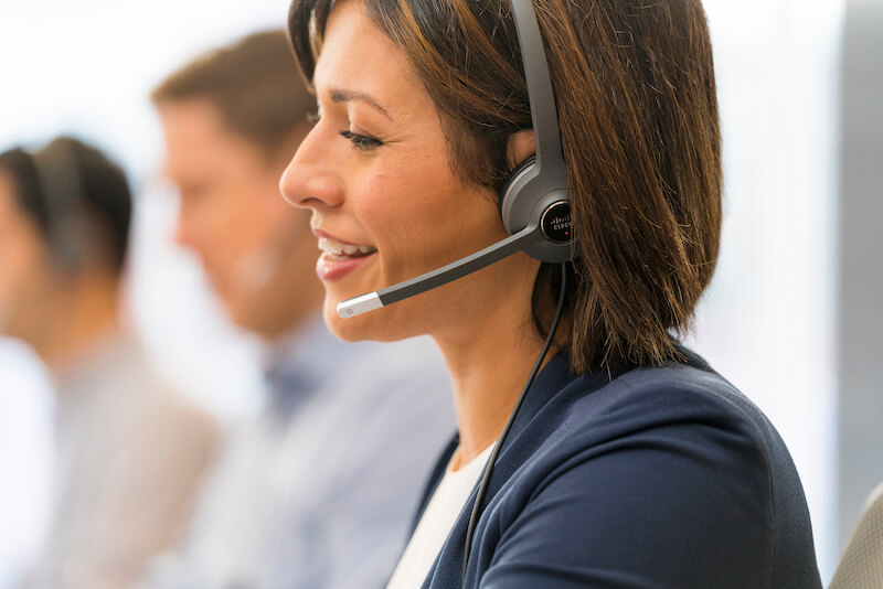 Eine Frau telefoniert &uuml;ber das Headset im B&uuml;ro