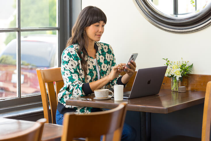 Eine Frau nutzt das G&auml;ste-Wifi in einem Caf&eacute;