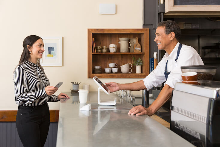 Eine Frau nutzt das Gästeinternet an der Kasse eines Cafés